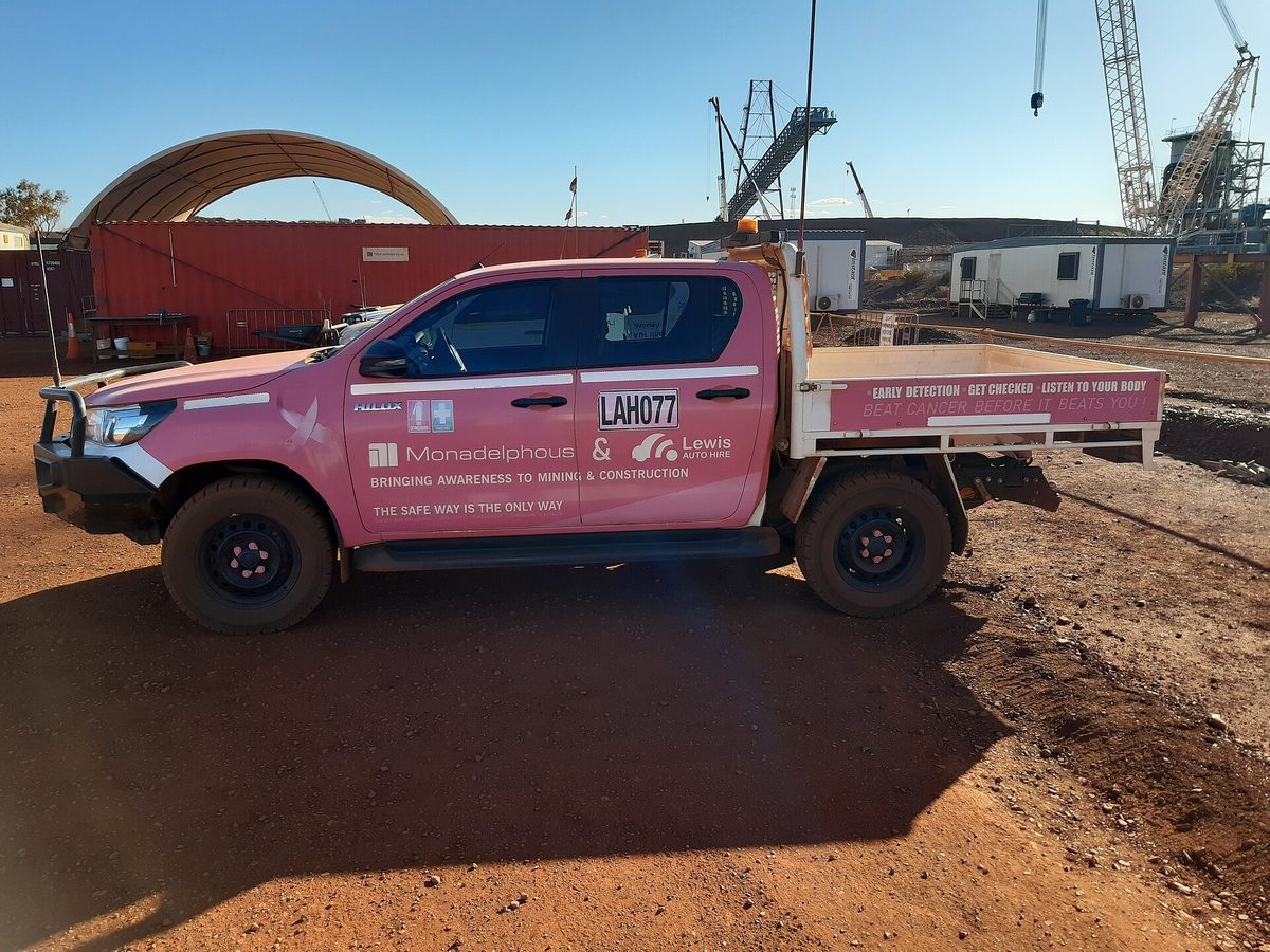 Dual cab utility with tray body and site flag on red ground, Pilbara